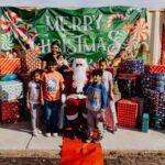 A group of children standing around santa clause.