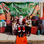 A group of people standing around santa clause.