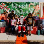 A group of people standing around santa clause.