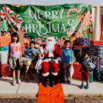 A group of children standing around santa clause.