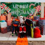 A man in santa suit sitting on the ground next to presents.