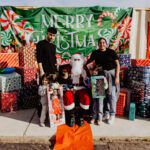 A group of people standing around santa clause.