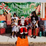 A group of people standing around santa clause.