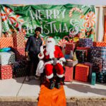 A man sitting on the ground next to santa clause.