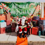 A person sitting on santa 's lap in front of many presents.