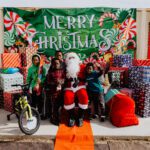 A group of children standing around santa clause.