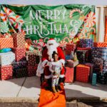 A child sitting in santa 's chair with his / her father.