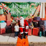 A little girl standing next to santa clause.