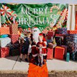 A group of children standing around santa clause.