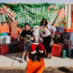 A group of people standing around santa clause.