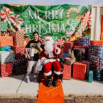 A person sitting on santa 's lap in front of a sign.