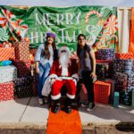 A group of people standing around santa claus.