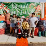 A group of people standing in front of some christmas decorations.