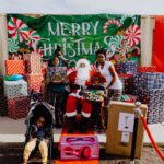 A group of people standing around santa clause.