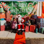 A person sitting on santa 's lap in front of many presents.