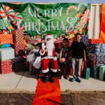 A group of people standing around santa clause.