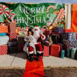 A child sitting on santa 's lap in front of many presents.