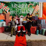 A person standing next to santa clause in front of some presents.