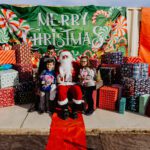 A group of people sitting around santa clause.