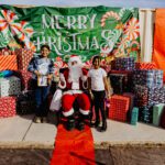 A group of people standing around santa clause.