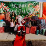 A woman and child posing with santa clause.