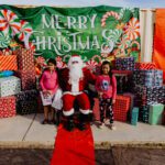 A child and an adult posing with santa claus.