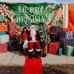 A group of people standing around santa clause.