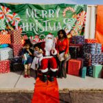 A group of people sitting around santa clause.