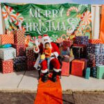 A child sitting on santa 's lap in front of many presents.