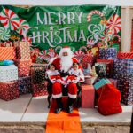 A santa clause sitting in front of many presents.