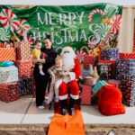 A group of people standing around santa clause.