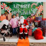 A group of people standing around santa clause.