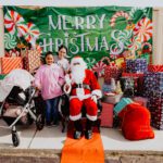 A group of people standing around santa clause.