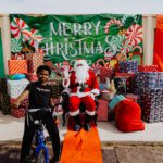 A man on a bike next to santa clause.