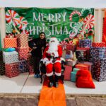 A person sitting in front of a santa clause statue.