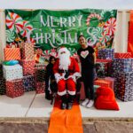 A group of people standing around santa clause.