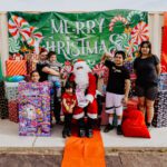 A group of people standing around santa clause.