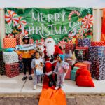 A group of children standing around santa clause.