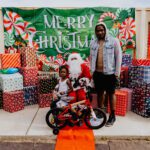 A man and boy standing next to santa clause.