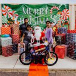 A group of people standing around a santa claus bike.