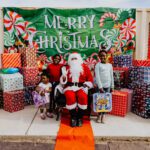 A group of people standing around santa clause.