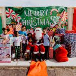 A group of children standing around santa clause.