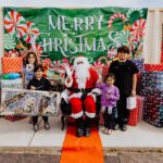 A group of people standing around santa clause.