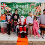 A group of people standing around santa clause.