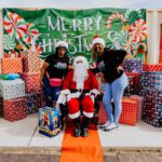 A group of people standing around santa clause.