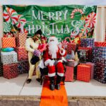 A man and woman standing next to santa clause.