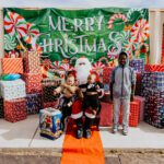 A group of people standing around santa clause.