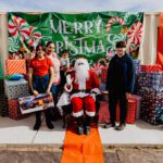 A group of people standing around santa clause.