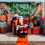 A group of people standing around santa clause.