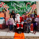 A group of children standing around santa clause.